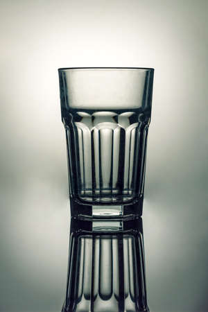 Empty highball glass on a gray background with a beautiful reflectionの写真素材