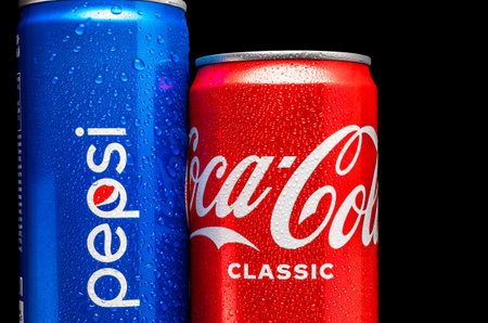 Blue can of Pepsi and red can of Coca-Cola with water droplets together on a black background....
