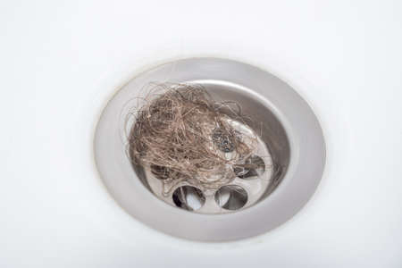 Close-up of a bundle of loose hair obstructing the bathroom drain. Hair clogging the drainの写真素材