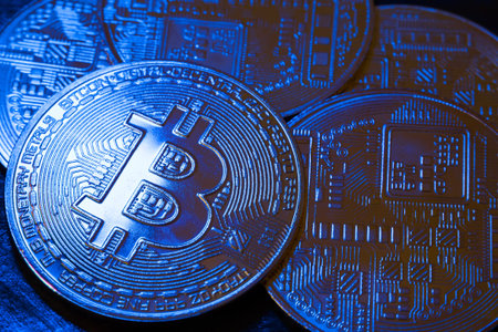 BTC coins in blue light on a dark background. bitcoin cryptocurrency. blockchain technology....