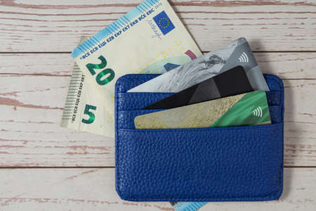Top view blue wallet with bank cards and Euro bills against a wooden Close-upの写真素材