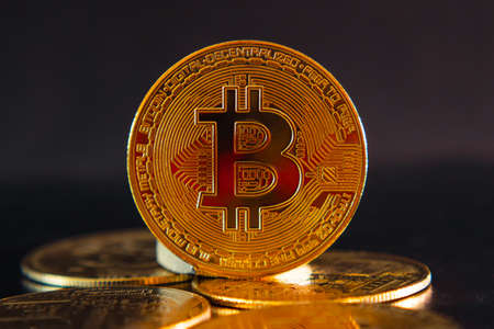 Bitcoin coin stands on scattered coins on a dark background. BTC cryptocurrency. blockchain technology. close-up. beautiful red lightの写真素材