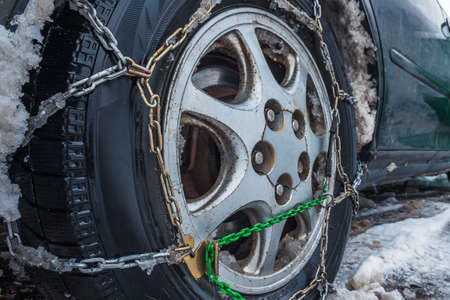 Close-up of a car wheel with snow chains. The fenders of the car are forgotten by the muddy snow. selective focus. The concept of safety on snowy roadsの写真素材