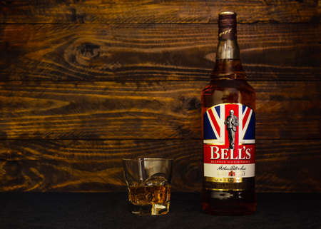 Bottle of Bell's Scotch Whiskey and a glass with ice on a dark wooden background. Bell's is the best-selling scotch in Great Britain for the past 30 years. Russia, Krasnodar, December 11, 2021のeditorial素材