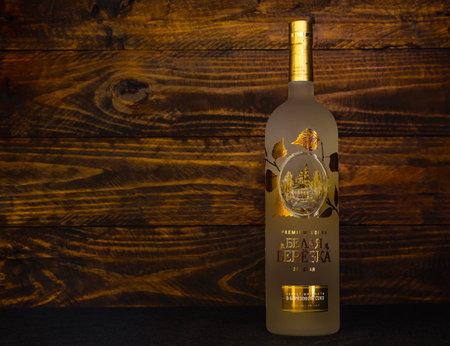 A bottle of Russian vodka Belaya Beryoka Golden on a dark wooden background. Vodka includes alcohol, birch sap, honey and sea buckthorn berries. Russia, Krasnodar, December 11, 2021のeditorial素材