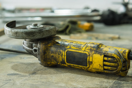 Yellow dirty angle grinder. close-up. Electric tool lying on a table in the shop. Specialized tools...