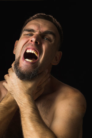 Portrait of young man with beard, hands around throat, screaming. Person holding on to sore neck and...