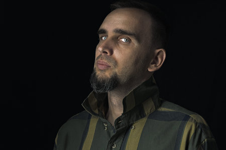 Beautiful bearded man in a studio in an unobtrusive way. Portrait of a sexy man in a checkered shirt...