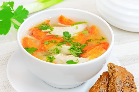 Chicken soup with vegetables in white bowl on a tableの写真素材