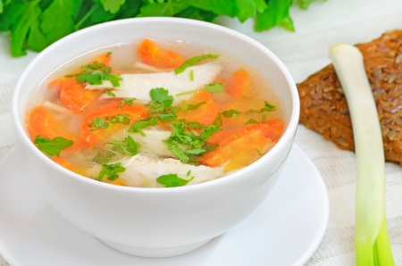 Chicken soup with vegetables in white bowl on a tableの写真素材