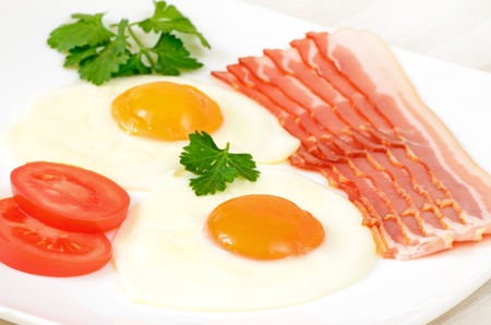 Breakfast with fried eggs, bacon and slices tomatoesの写真素材