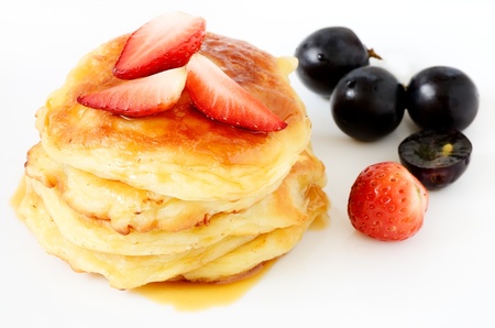 Homemade cheese pancakes and strawberries and grapes on white backgroundの写真素材