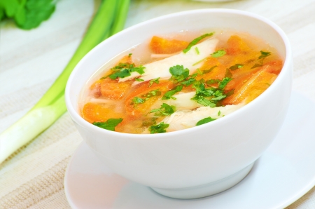Chicken soup with vegetables in white bowl on a tableの写真素材