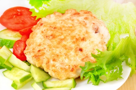 Chicken cutlet with slices of tomato, cucumber and lettuce leavesの写真素材