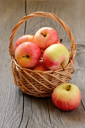 Apples in the wicker basket on a wooden tableの写真素材