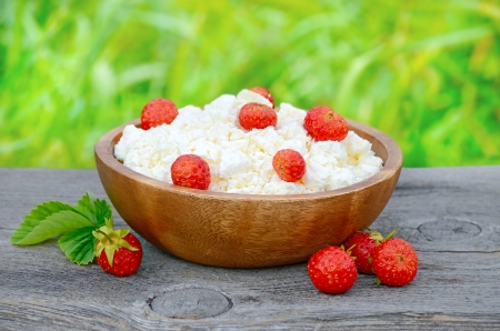 Fresh cottage cheese with strawberries in wooden bowlの写真素材