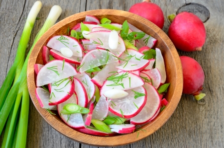 Radish salad in brown bowl on wooden tableの写真素材