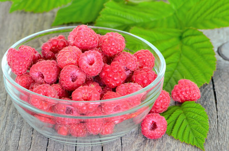 Raspberries in glass bowl on wooden table