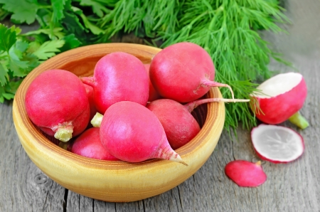 Radish in a brown bowl on wooden tableの写真素材