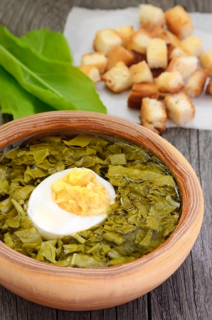 Sorrel soup with egg in brown bowl on the wooden tableの写真素材