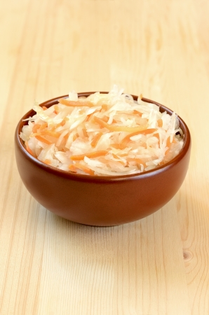 Sauerkraut in ceramic bowl on wooden tableの写真素材