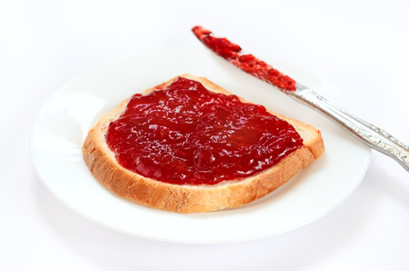 Bread with strawberry jam on a white plateの写真素材