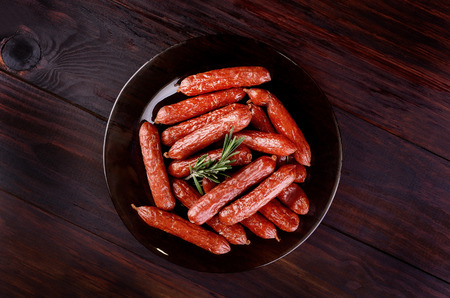 Smoked sausages on a plate on a wooden table, top viewの写真素材