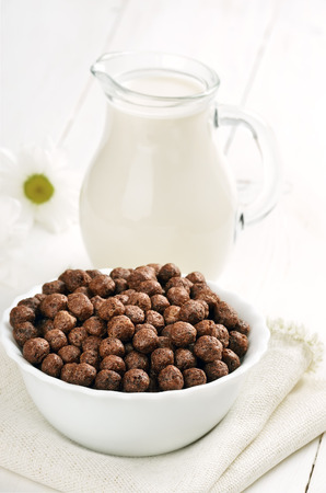 Cereal chocolate balls in bowl and jug of milkの写真素材