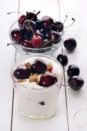 Yoghurt dessert with cherry and cookies on wooden tableの写真素材