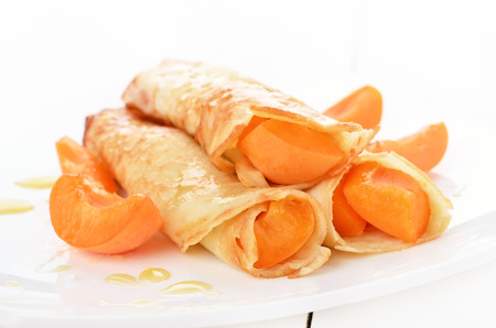 Crepes with apricot slices on white plateの写真素材