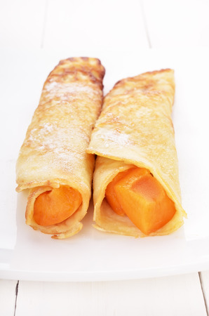 Crepes with apricot slices on white plateの写真素材