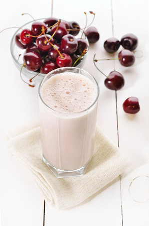 Cherry smoothie in glass on wooden tableの写真素材
