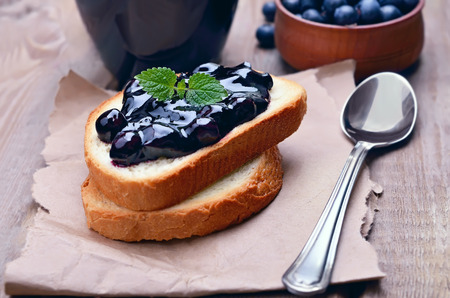 Toasted bread with blueberry jam on wooden tableの写真素材