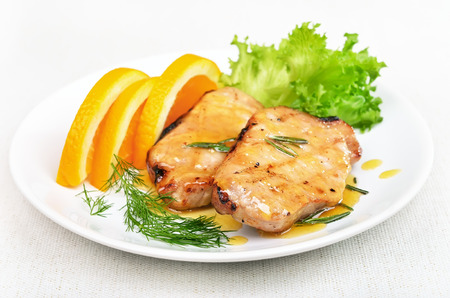 Pork chop with orange sauce on white plateの写真素材