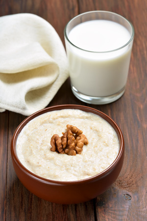 Healthy food. Oatmeal porridge with walnuts and glass of milk on wooden tableの写真素材