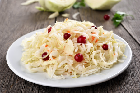 Pickled cabbage (sauerkraut) with cranberries on white plateの写真素材