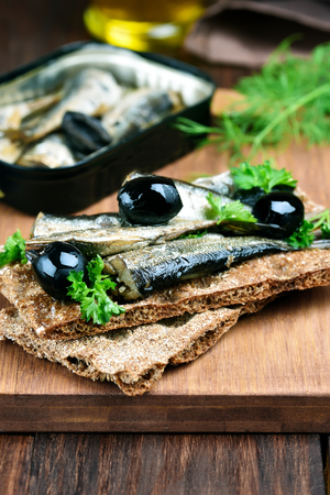 Fish sandwich with sprats, herbs and olivesの写真素材