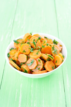 Carrot salad in bowl on green wooden tableの写真素材