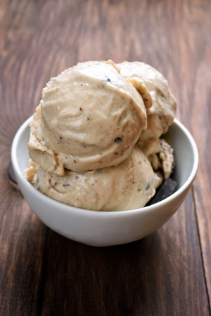 Scoops of homemade ice cream in bowl on wooden tableの写真素材