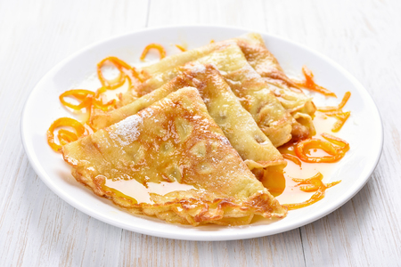 Pancakes with orange syrup on white wooden tableの写真素材