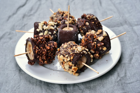 Frozen banana covered with chocolate and peanutsの写真素材