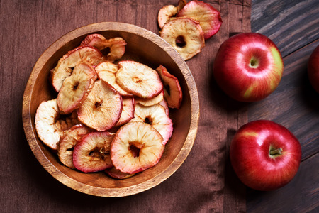Dehydrated apples chips in wooden bowl, top viewの写真素材