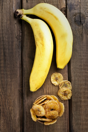 Banana chips and fresh fruits on wooden table, top viewの写真素材