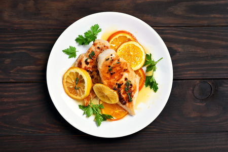Grilled chicken breast with orange sauce on wooden background, top viewの写真素材