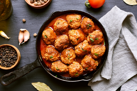 Meatballs with tomato sauce in frying pan on black background, top viewの写真素材