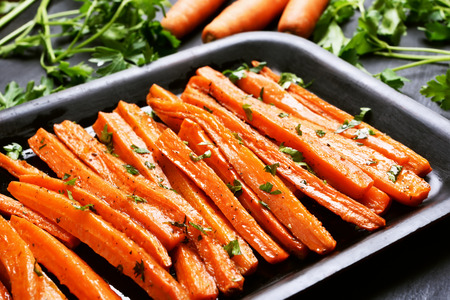 Fried carrots with green herbs in baking tray, close upの写真素材