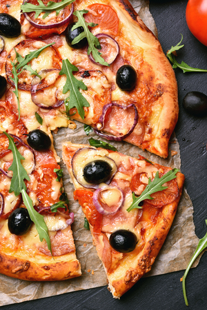 Sliced pizza with tomato, salami and olives, top viewの写真素材
