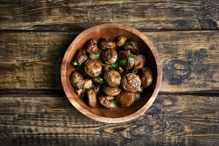 Fried mushrooms with onion in bowl on wooden background, top viewの写真素材