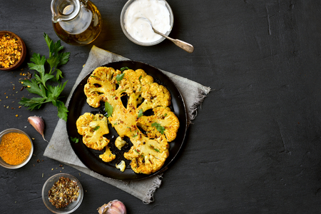 Baked cauliflower steak with herbs and spices on black background with copy space. Top viewの写真素材