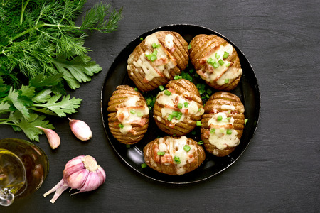 Stuffed potatoes with bacon, green onion and cheese on dark background. Dish for dinner. Top view, flat lay foodの写真素材